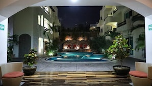 A pool area with a stone wall, seating, and potted plants.