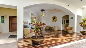 A lobby with a wooden floor, a large potted plant, and a reception desk.