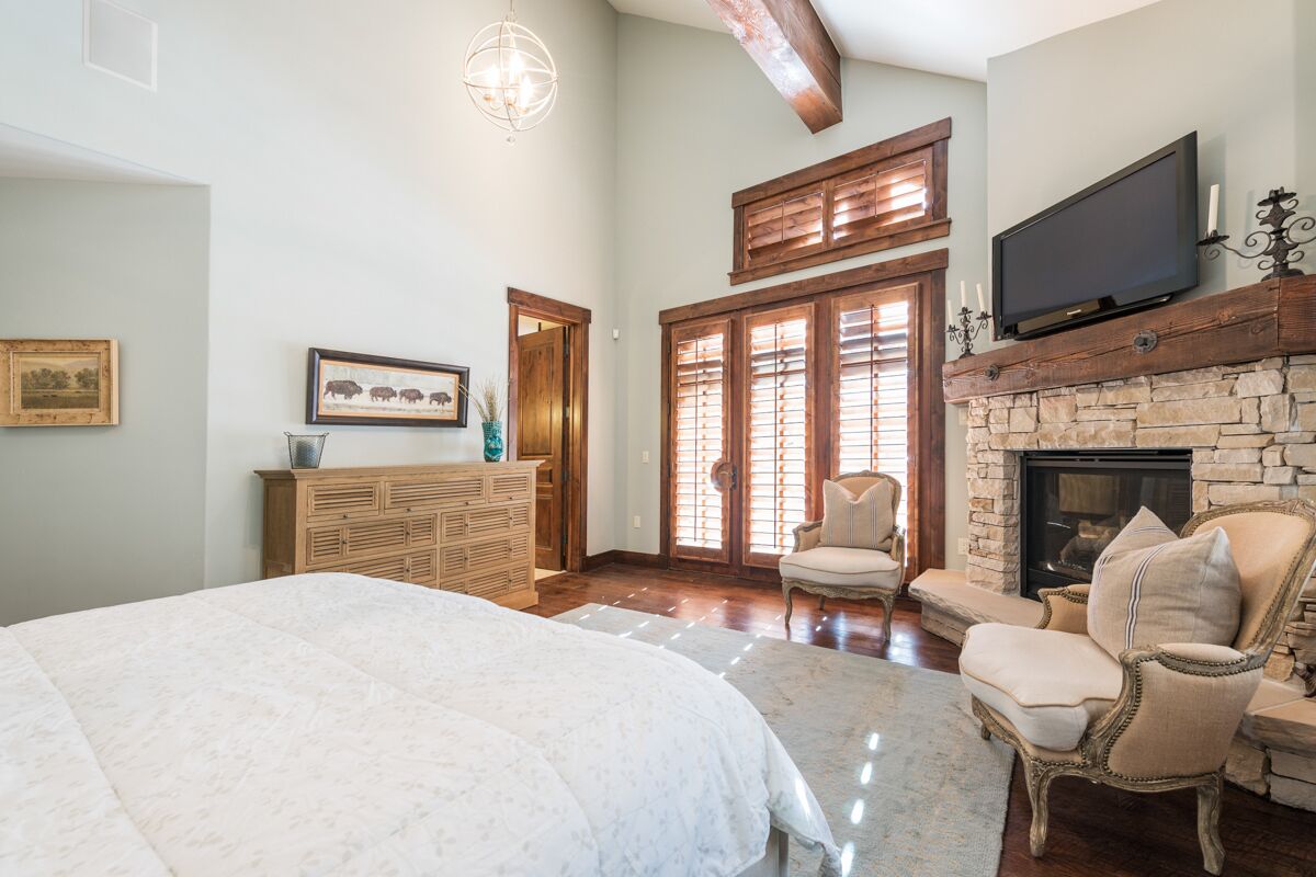 Une chambre spacieuse avec un grand lit, une cheminée, une télévision et une commode en bois.