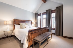 A bedroom with a large bed, a bench, two bedside lamps, and a window with curtains. - Last-Minute Savings! Cottage with Ski-in/Ski-out Access and Private Hot Tub! (Park City)