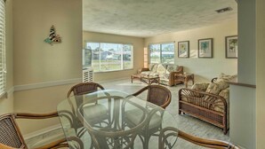 A spacious living room with a glass-top dining table surrounded by wicker chairs, a sofa, and a bed with patterned cushions. - Venice Home w/ Fire Pit & Grill: 2 Mi to Beach! (Venice)