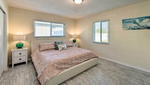 A bedroom with a bed, two bedside tables, a nightstand, and two windows. - Venice Home w/ Fire Pit & Grill: 2 Mi to Beach! (Venice)