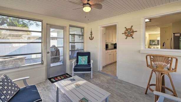 A cozy room with a ceiling fan, a dining table with a placemat, a bar stool, and a view of the kitchen through an open door. - Venice Home w/ Fire Pit & Grill: 2 Mi to Beach! (Venice)