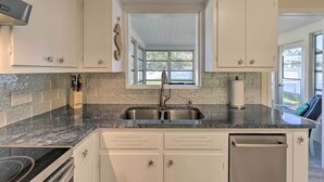 A kitchen with white cabinets, a granite countertop, a double sink, and a window above the sink. - Venice Home w/ Fire Pit & Grill: 2 Mi to Beach! (Venice)