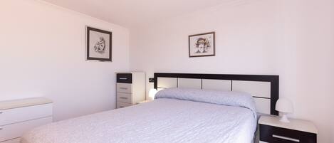 Une chambre à coucher avec un lit, une table de chevet, une commode et deux tableaux encadrés accrochés au mur.