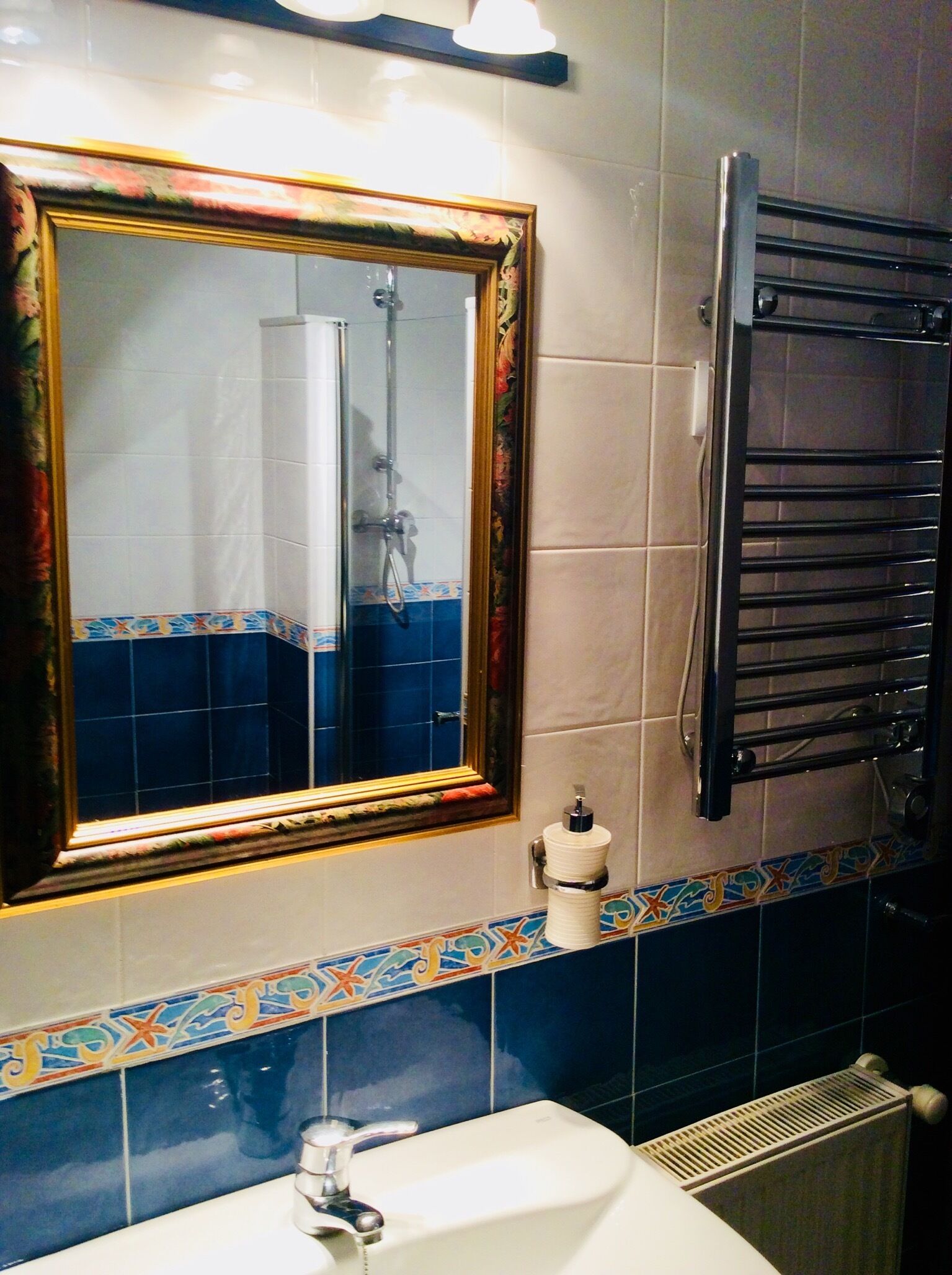 Un baño con lavamanos, espejo y perchero para toallas.