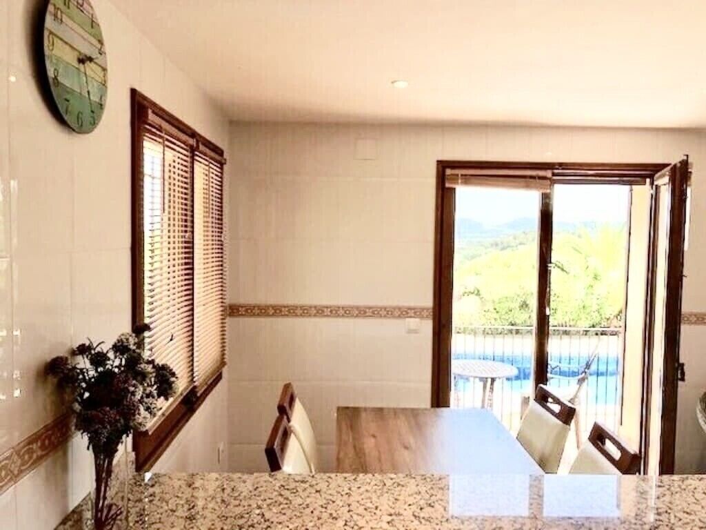 Una camera d'albergo con zona pranzo, orologio a parete e vista sull'esterno.