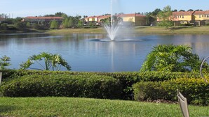 A lake with a fountain in the center, surrounded by well-maintained lawns and hedges. - Amazing Lake View : 4 Bed End Townhouse : Super Fast WiFi : Private Pool (Kissimmee)