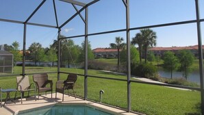 A pool area with a clear view of a lake and surrounding greenery, enclosed by a metal fence. - Amazing Lake View : 4 Bed End Townhouse : Super Fast WiFi : Private Pool (Kissimmee)