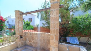 A stone structure with steps leading up to a platform, surrounded by greenery and a building in the background. - Holiday villa with swimming pool near the Paphos coast (Paphos)