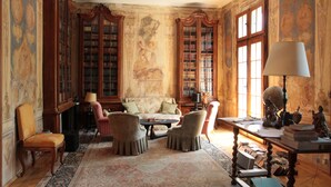 Une pièce avec un canapé, des fauteuils, une table avec des livres et une lampe.