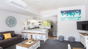 Una sala de estar moderna con un sofá, una mesa de centro y una cocina al fondo.