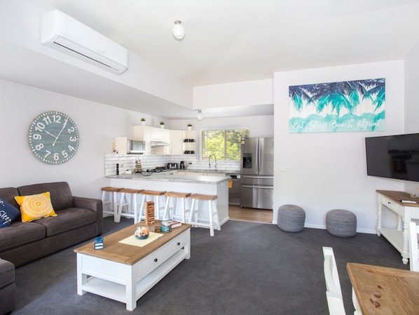 A modern living room with a sofa, coffee table, and a kitchen area in the background.