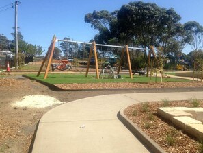 A playground with swings and a small green area.