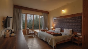 Una camera da letto con un letto grande, una scrivania in legno, una televisione e una finestra con tende.