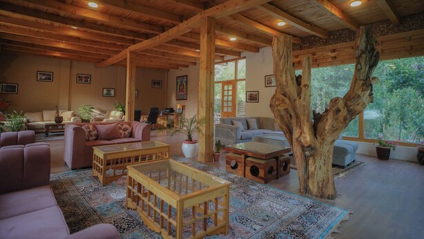 Un ampio soggiorno con travi in legno, un grande tronco d'albero come elemento centrale e diverse zone relax.