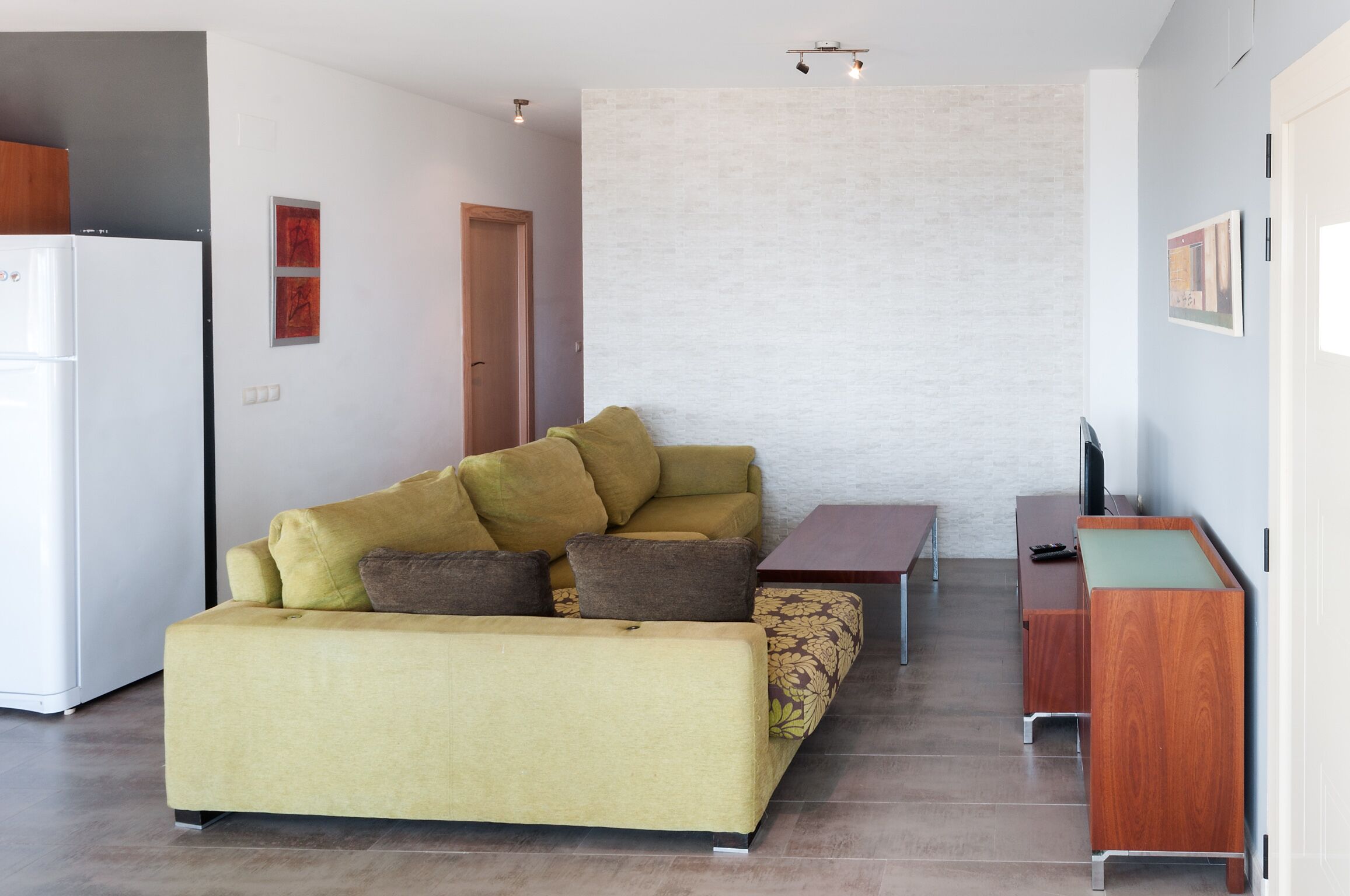 A modern living room with a sofa, a small table, and a wooden cabinet.