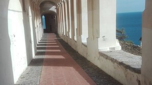 Un pasillo con columnas blancas y una alfombra roja que conduce a vistas del mar.