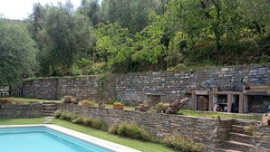 Una piscina con un muro de piedra y escalones que conducen a un edificio de fachada de piedra.