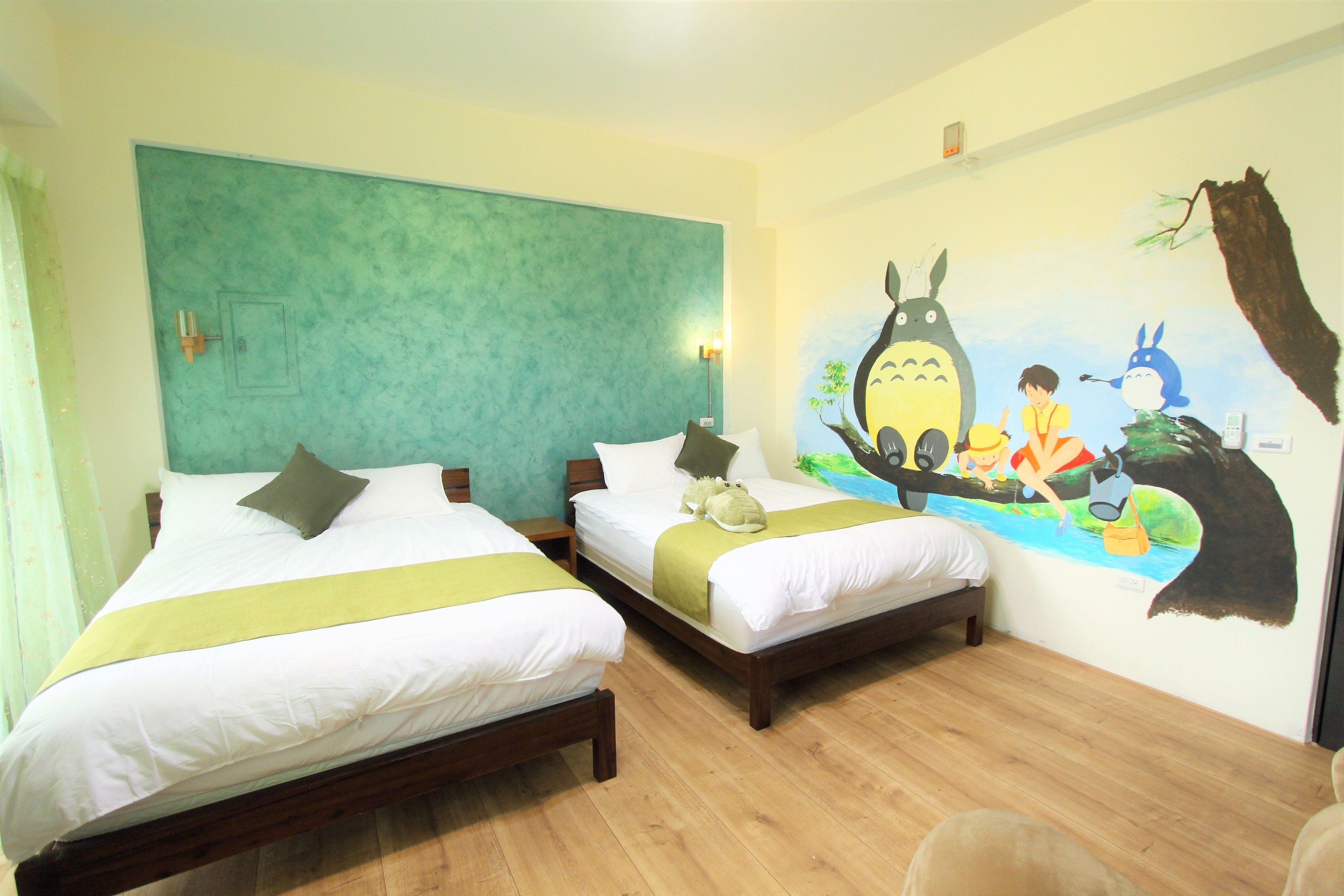 Une chambre d’hôtel avec deux lits, une fresque murale et un plancher en bois.