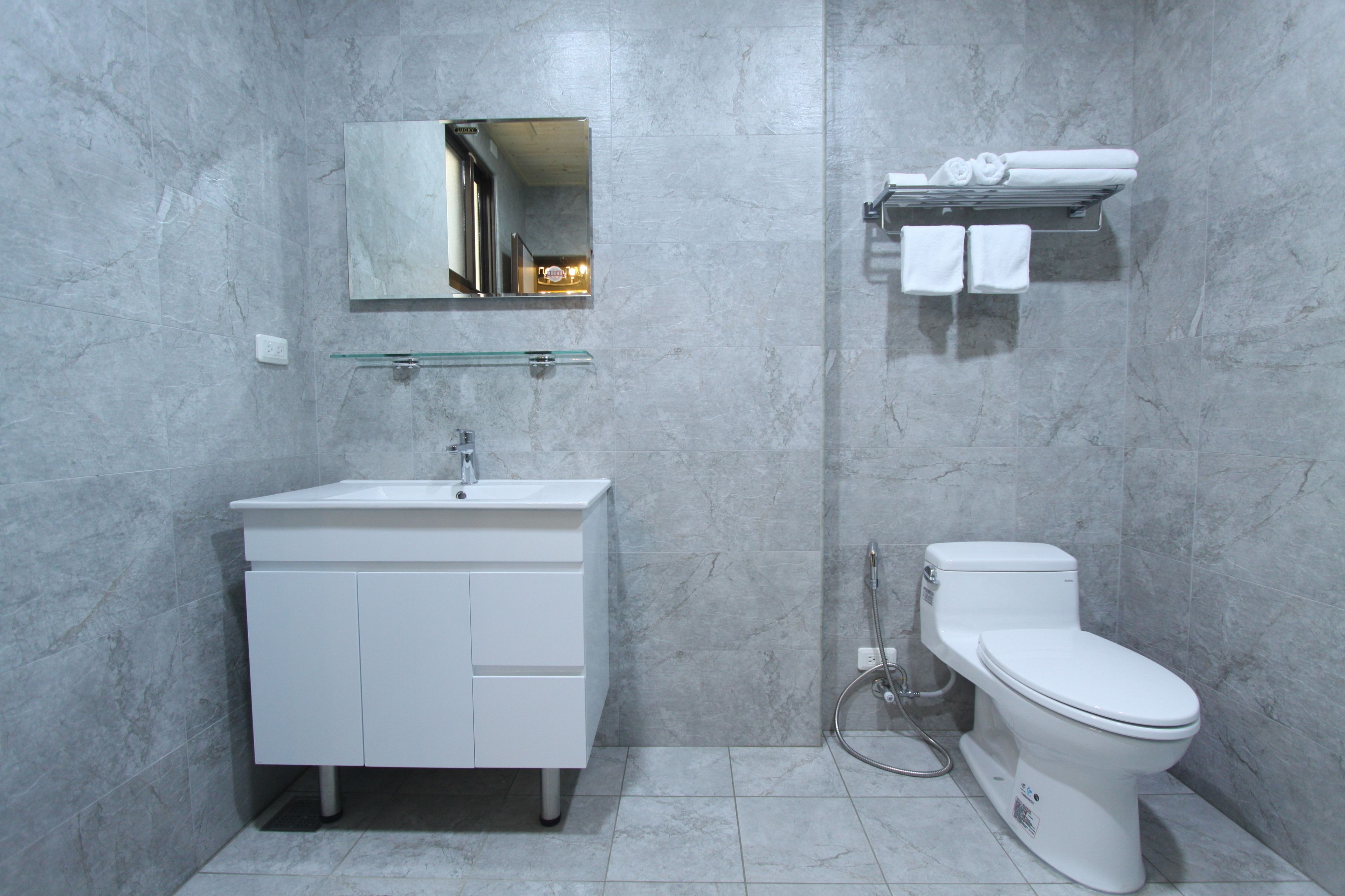 A modern bathroom with a white sink, mirror, and toilet.