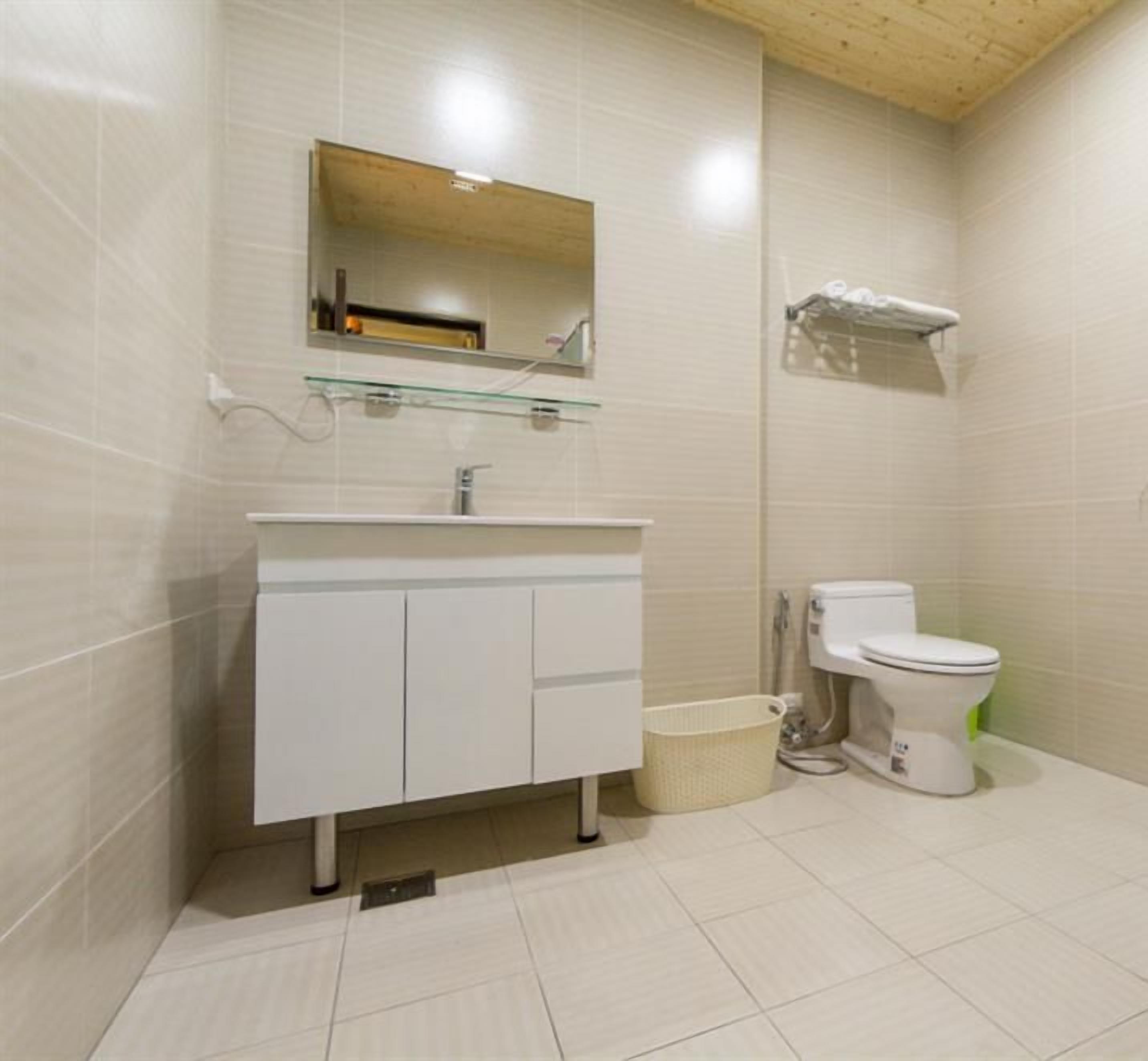 A bathroom with a white sink, mirror, and toilet.