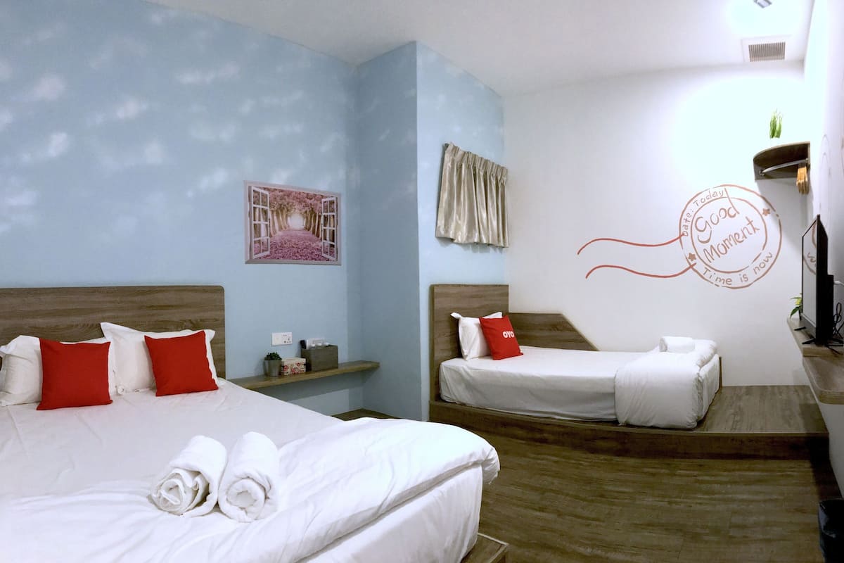 Ein Hotelzimmer mit zwei Betten, einem kleinen Tisch, einer Ablagefläche und einer Wanddekoration.