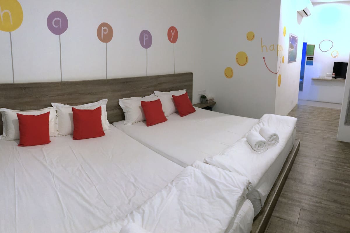 Ein Doppelbett mit weißen und roten Kissen, ein Holzkopfende und eine Wand mit Buchstaben und Smileys.