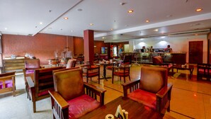 A hotel lobby with multiple seating areas, a bar, and a reception desk. - Shivam Resorts (Jaipur)