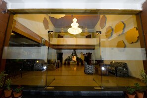 A lobby with a chandelier, potted plants, and a seating area. - Shivam Resorts (Jaipur)