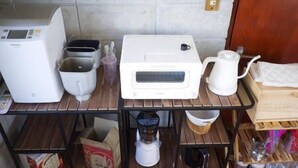 A kitchen counter with a coffee maker, toaster, and kettle. - Happy coral (Higashi)