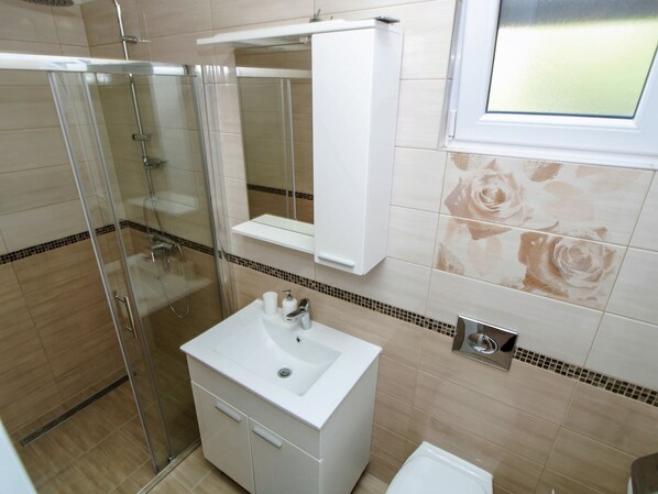 A bathroom with a glass shower enclosure, a white sink with a mirror above it, and a toilet. - Adria View, Apartment Dino, Whirlpool, pool (Makarska)