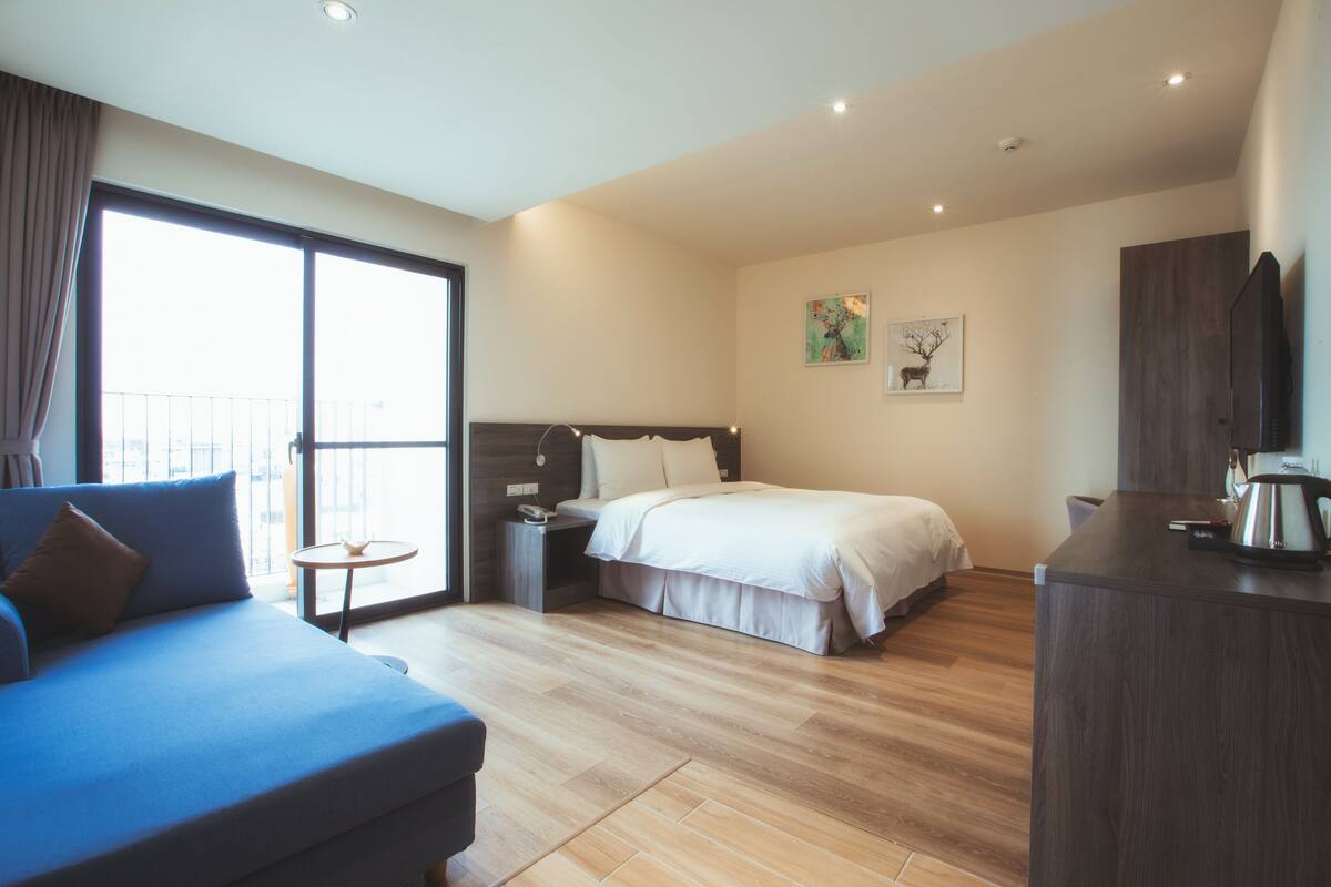 Ein modernes Hotelzimmer mit einem großen Bett, einer Couch, einem kleinen Tisch und einem Fernseher.