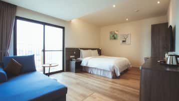 A modern hotel room with a large bed, a sofa, a small table, and a TV.