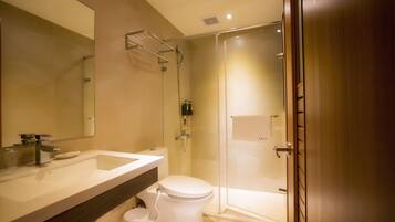 A modern bathroom with a large mirror, a sink, a toilet, and a glass-enclosed shower area.
