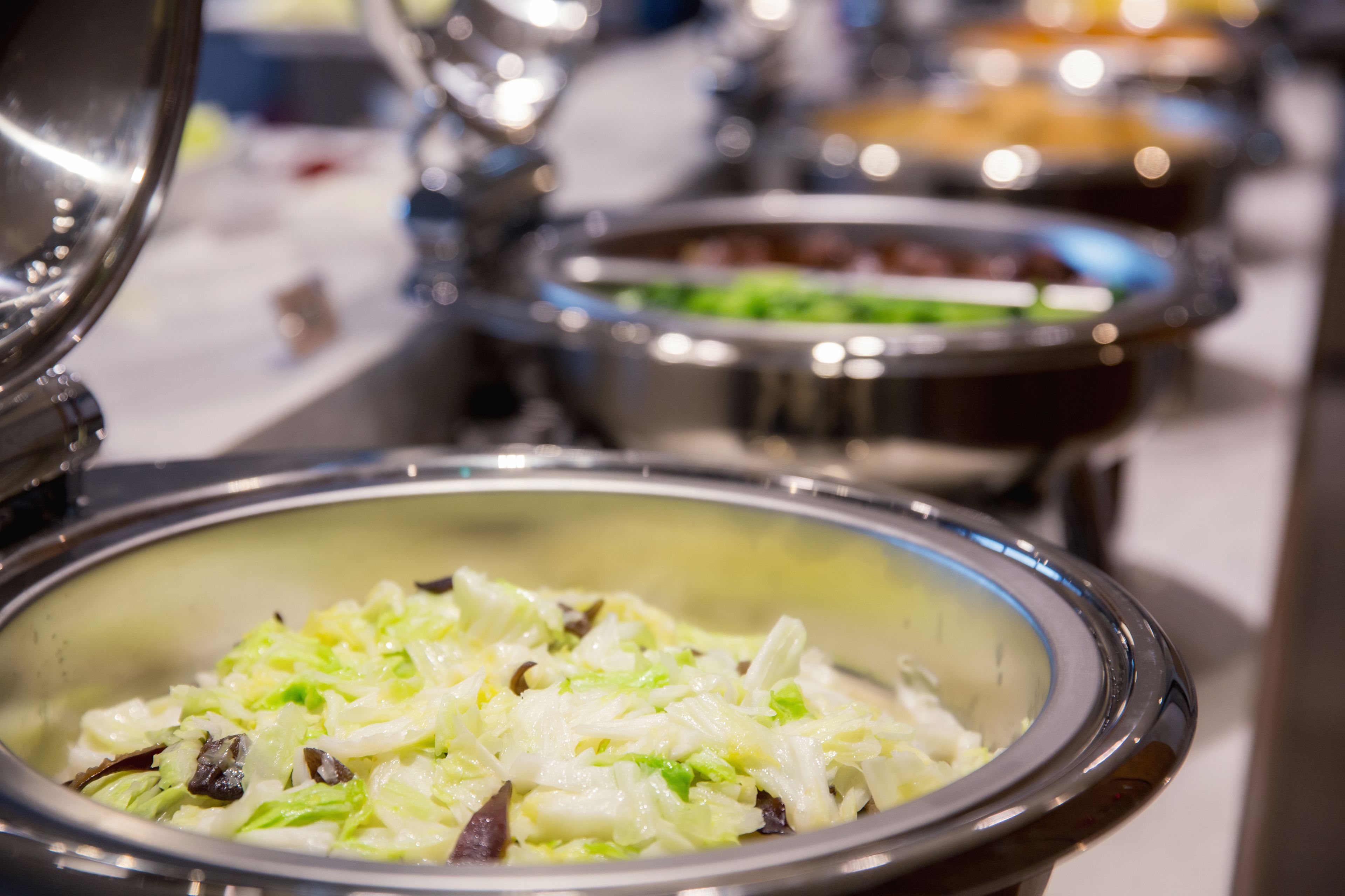 A buffet with various dishes, including a bowl of coleslaw.