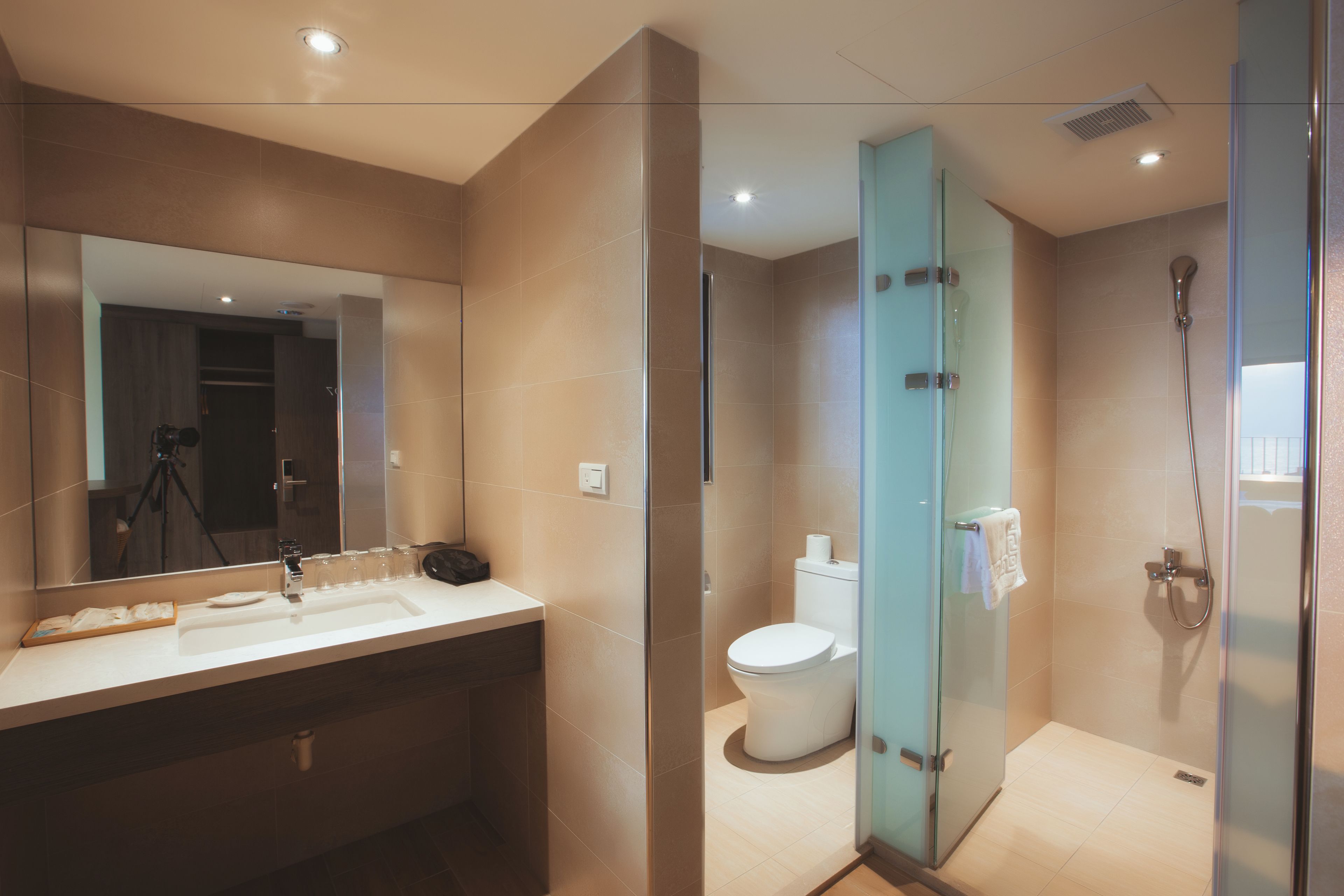 Un baño moderno con cabina de ducha de vidrio, un espejo grande y tocador con lavamanos y toallero.