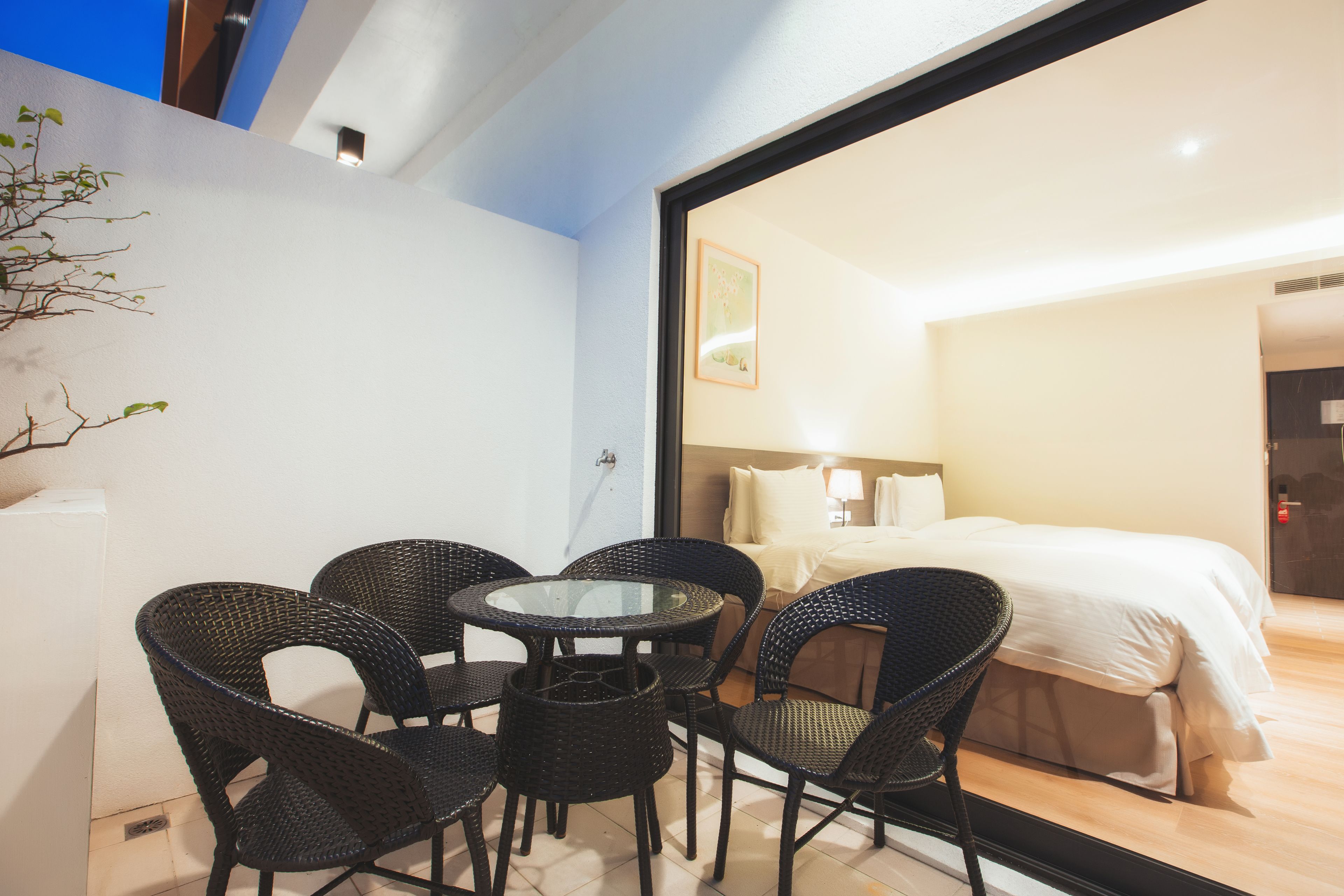 A hotel room with a bed, a bedside table, a lamp, and a window.