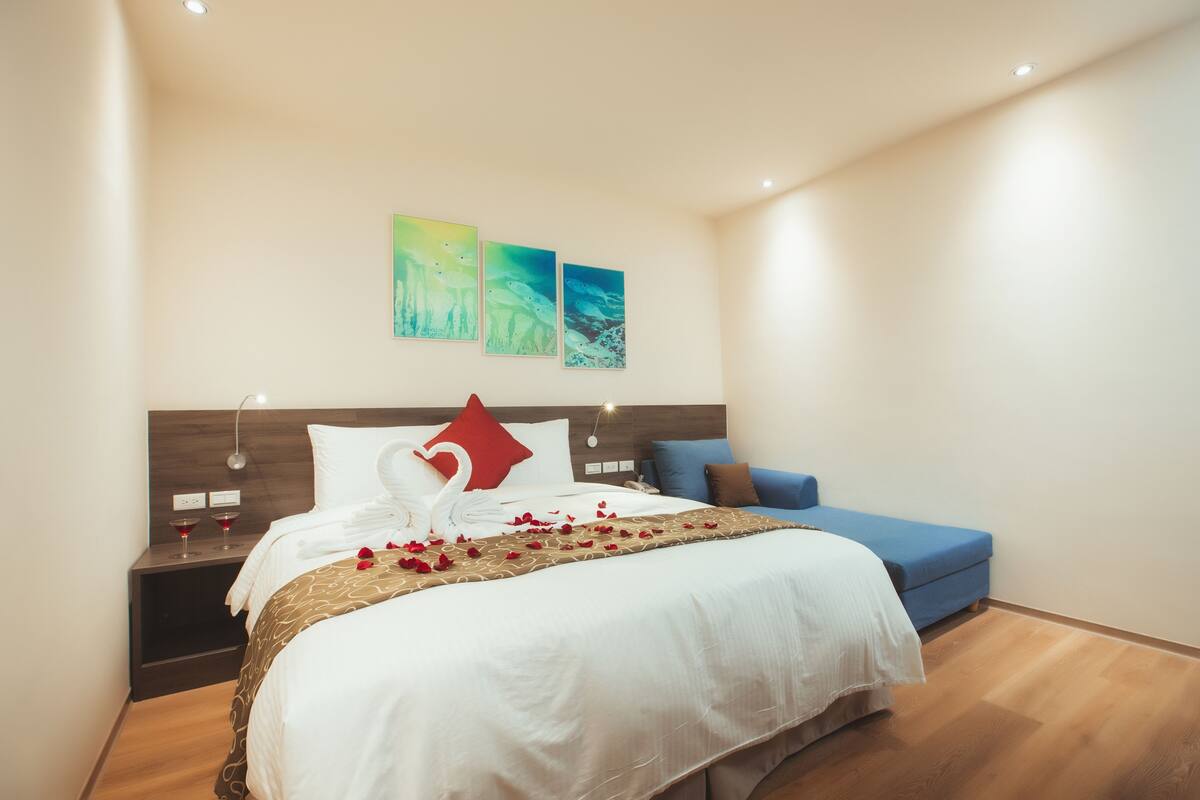 Ein Hotelzimmer mit einem großen Bett, einem blauen Sofa und zwei an der Wand befestigten Bildern.