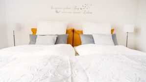 Un lit bien fait, avec du linge de lit blanc et un panneau décoratif mural, dans une chambre d’hôtel.