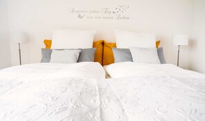 Un lit bien fait, avec du linge de lit blanc et un panneau décoratif mural, dans une chambre d’hôtel.
