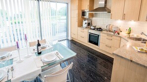 A modern kitchen with a dining area, featuring a large window, a built-in oven, and a microwave. - Exclusive apartment with water view - Apartment Meierwik (Glücksburg (Ostsee))