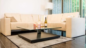 A modern living room with a beige sofa, a glass coffee table, and a lamp. - Exclusive apartment with water view - Apartment Meierwik (Glücksburg (Ostsee))