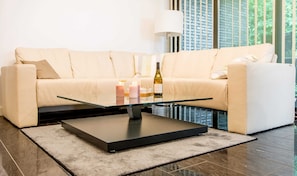 A modern living room with a beige sofa, a glass coffee table, and a lamp. - Exclusive apartment with water view - Apartment Meierwik (Glücksburg (Ostsee))