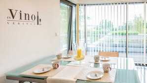Un coin repas avec une table dressée pour quatre personnes, un chandelier en guise de décoration centrale et une vue sur un parking à travers de grandes fenêtres.