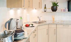 A modern kitchen with a sink, countertop, and wooden cabinets. - Exclusive apartment with water view - Apartment Meierwik (Glücksburg (Ostsee))
