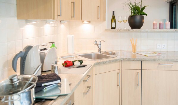 A modern kitchen with a sink, countertop, and wooden cabinets.