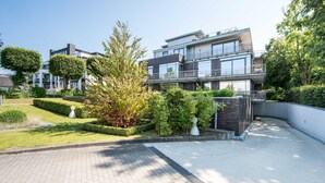 A modern multi-story residential building with a well-maintained garden and paved pathways. - Exclusive apartment with water view - Apartment Meierwik (Glücksburg (Ostsee))