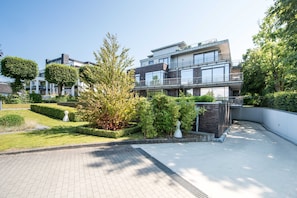 A modern multi-story residential building with a well-maintained garden and paved pathways. - Exclusive apartment with water view - Apartment Meierwik (Glücksburg (Ostsee))