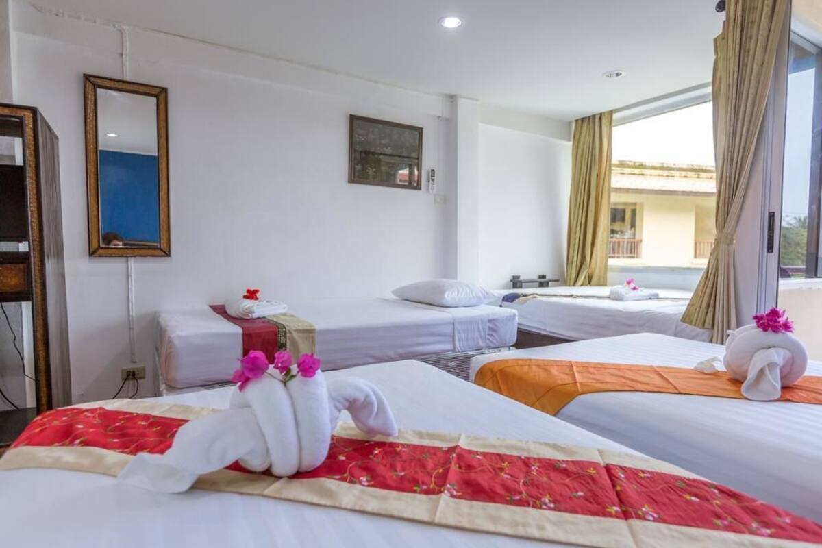 A hotel room with two beds, a desk, and a window with curtains.